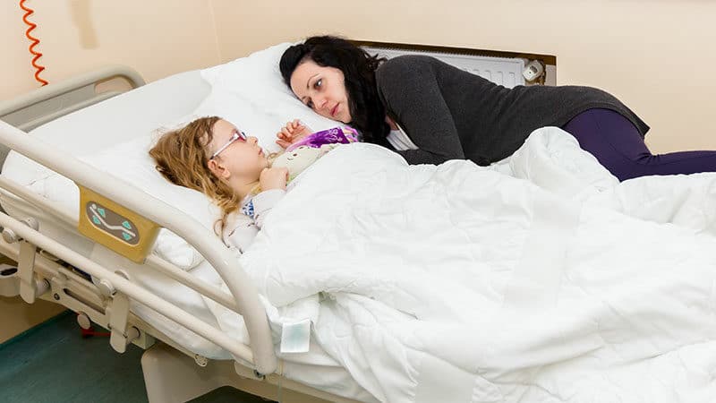 Mom comforts sick child in hospital bed